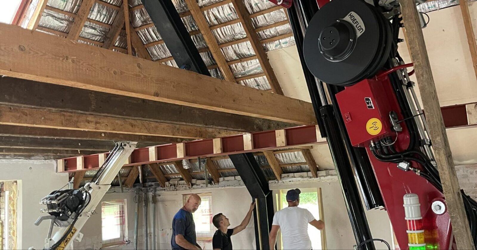 Mini hijskraan plaatst een staalconstructie onder een bestaande constructie